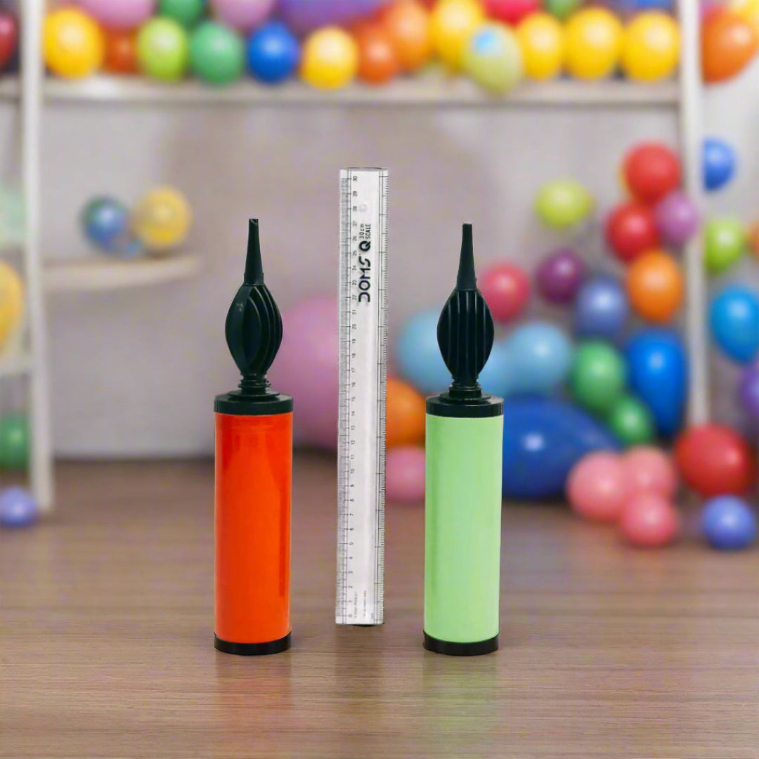 Two balloon pumps, one orange and one green, standing next to a ruler for scale.