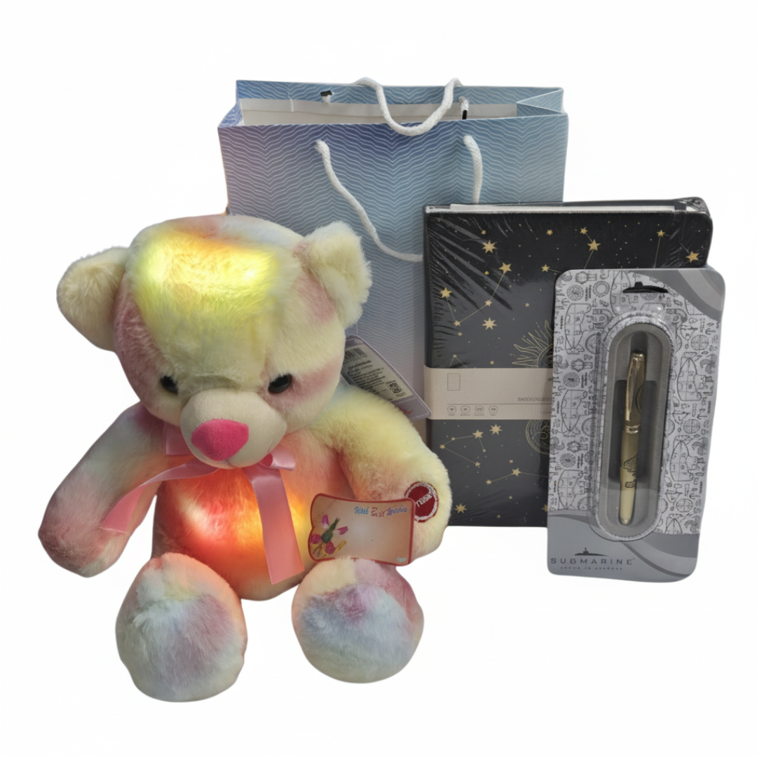 A gift set including a multicolored teddy bear, a black executive diary, a silver submariner pen, all packaged in a designer gift bag with a 'Happy Women's Day' card.