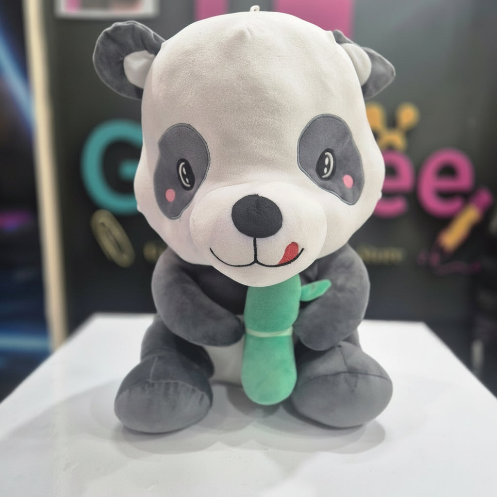 A plush toy depicting a cartoon-style panda holding a green bamboo shoot.