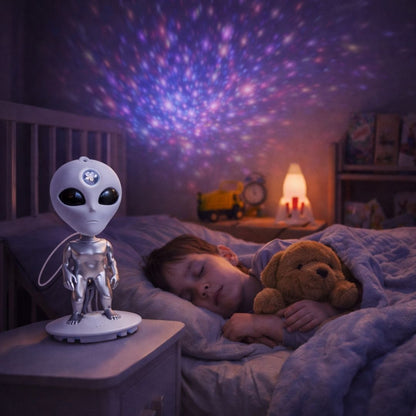 Child sleeping in bed with an alien lamp and teddy bear, room lit with star projector