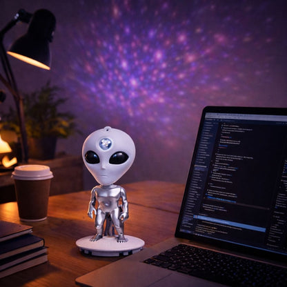 Alien figure on a desk with a laptop and lamp in a room with a starry night light projection.