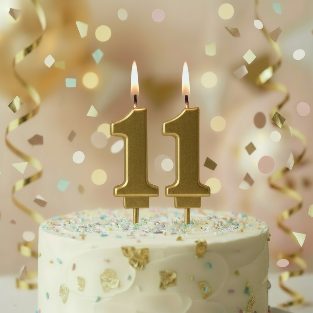 Cake with number 11 candles on a festive background with confetti and ribbons.