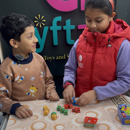 Two children playing with face emoji cube puzzle toys on a table in front of a screen displaying a store logo.