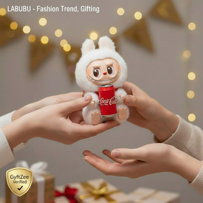 Two hands holding a small plush toy with a Coca-Cola design against a festive background. LABUBU Doll