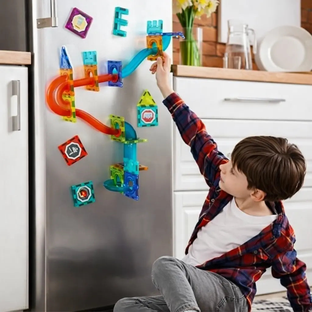 Child playing with a colorful magnetic building set on a refrigerator in a kitchen.