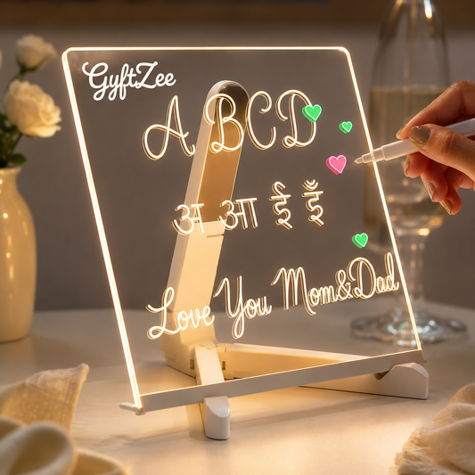 Light-up board with 'Love You Mom&Dad' message on a table with flowers and a glass.