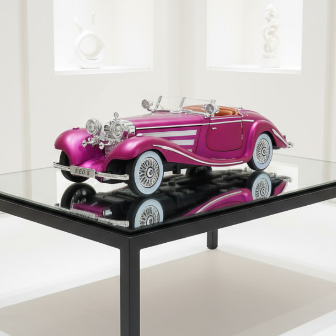Model of a vintage pink car on a glass table with a white curtain background